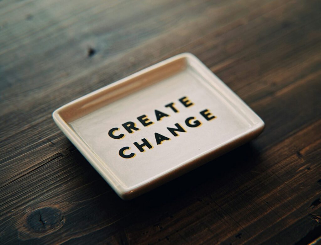 “Create Change” text on a tray placed on a wooden surface representing transformation and innovation.
